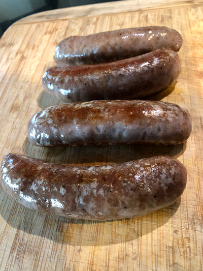 Four veniaon sausages on a wooden cutting board